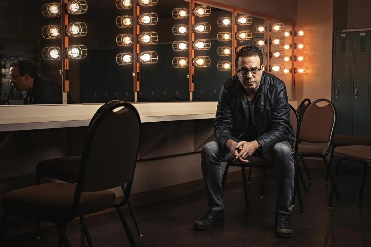 A man sitting in a chair with lights on a mirror