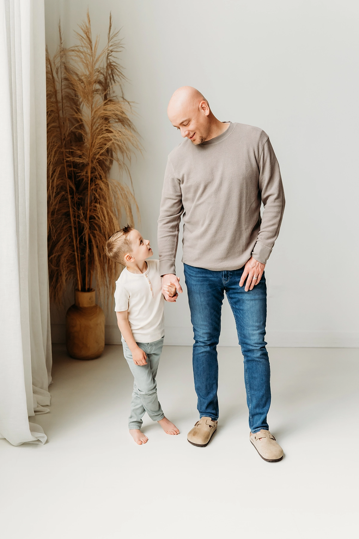 Father and sone pose by window flooding room with natural light for a Father's Day portrait.