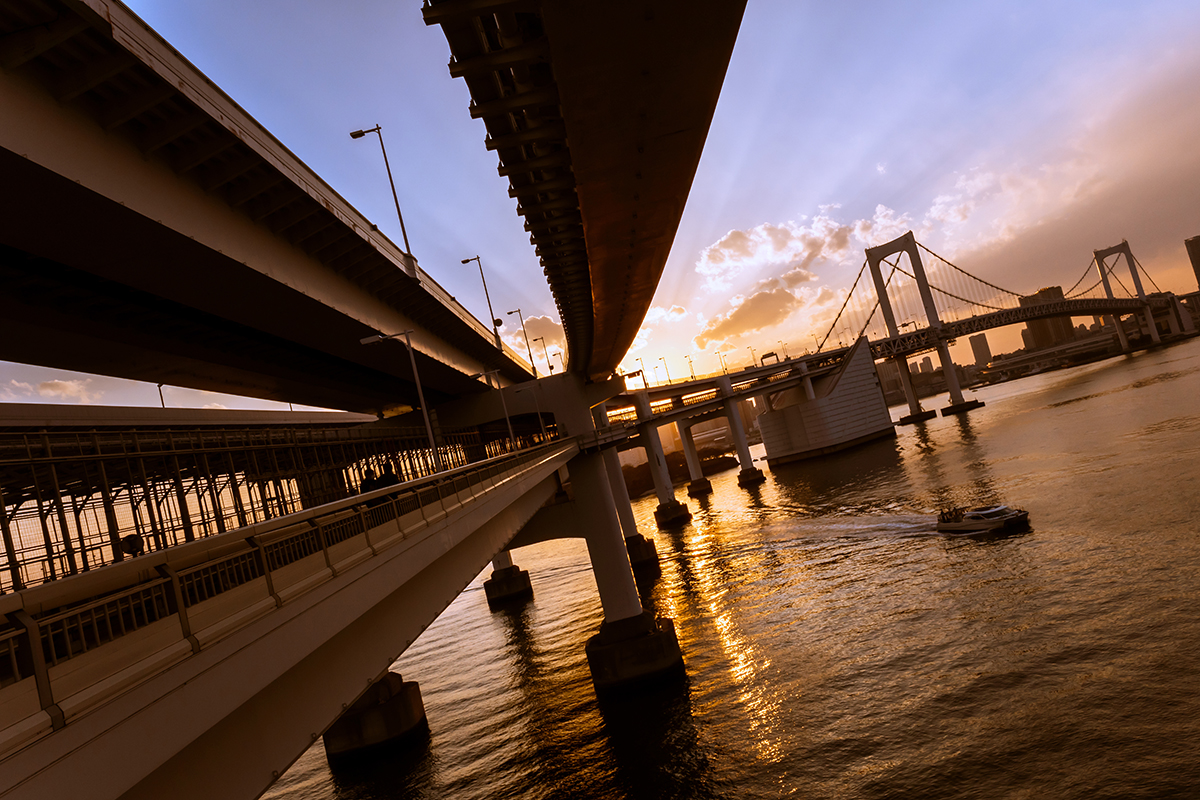 Tilted view of a bridge and highway structure at sunset.