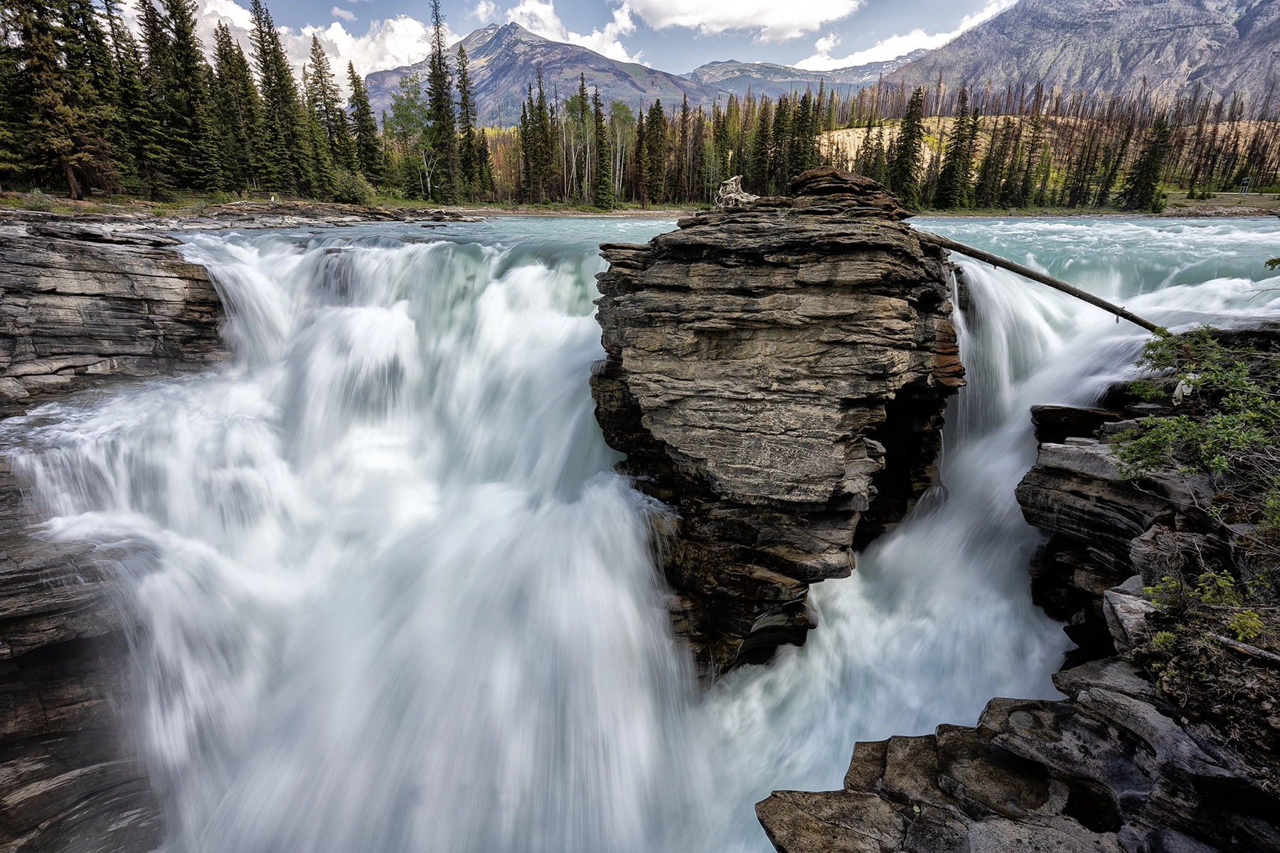 Une cascade d'eau vive contre des montagnes en contrebas, réalisée en utilisant la photographie à longue exposition.
