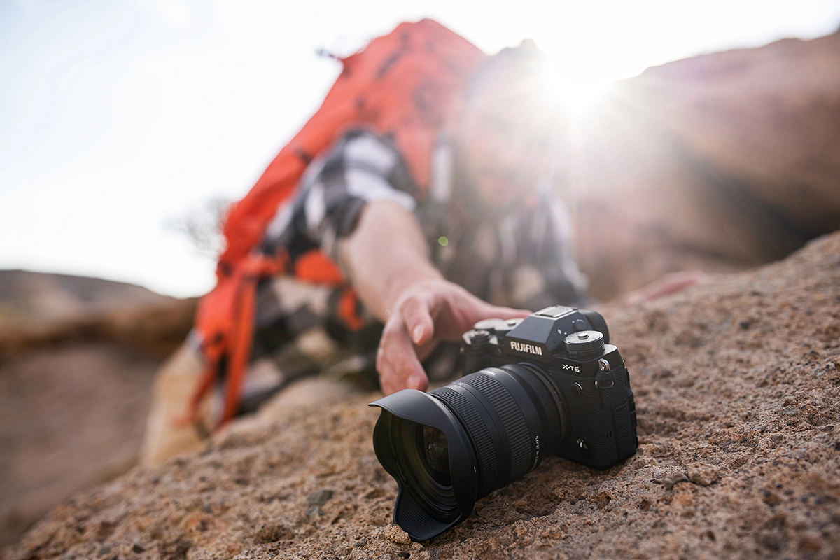 Homme saisissant un zoom grand angle Tamron 11-20mm F2.8 sur un appareil photo Fujifilm de la série X.