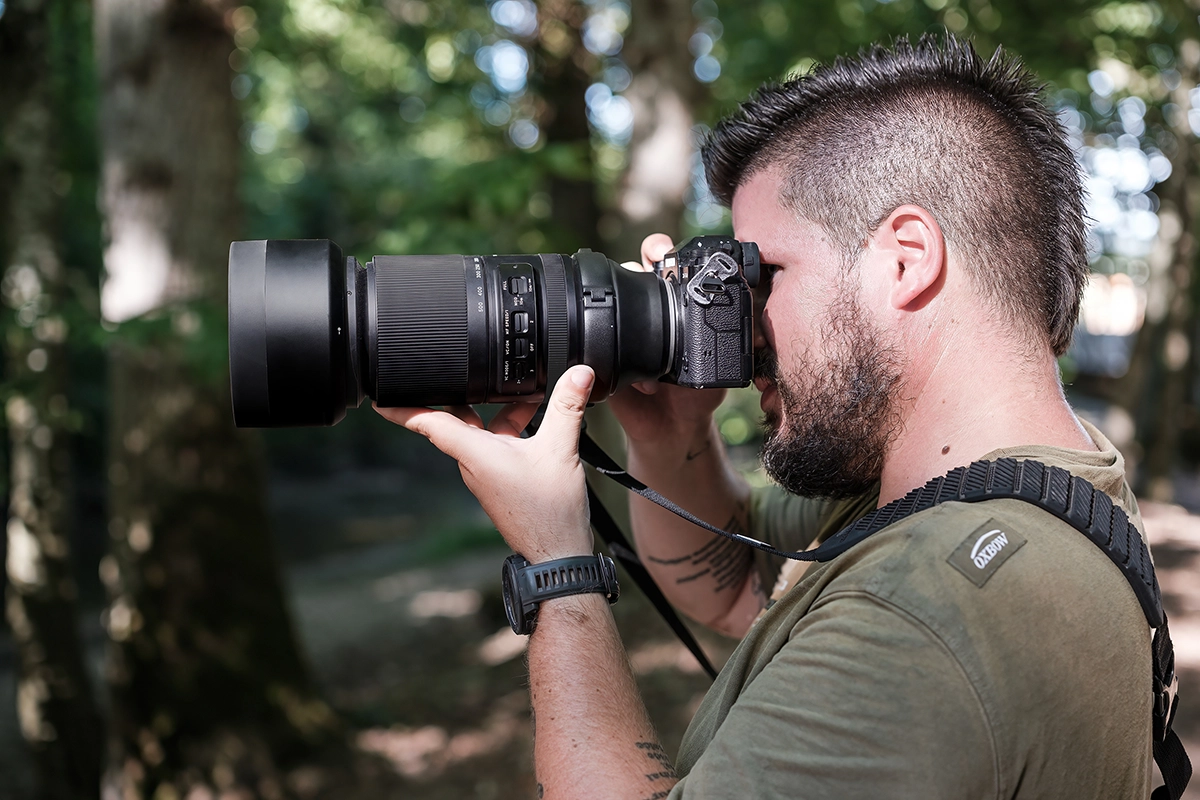 Homme tenant un ultra-téléobjectif Tamron 150-500 mm sur un appareil photo numérique Fujifilm.
