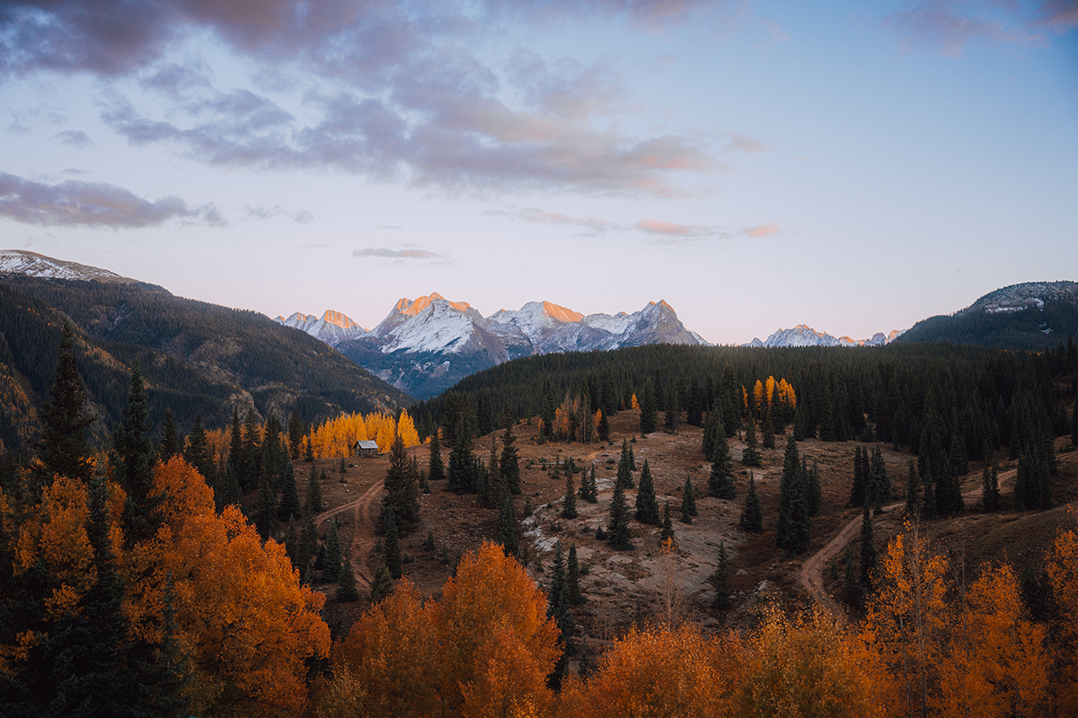 © Jonny Hill Orange color trees with snow covered mountains in the background