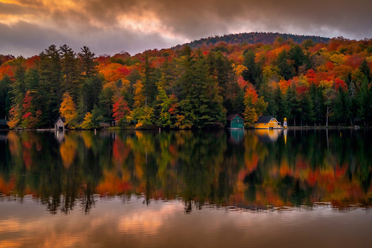 A lake with a forest of colorful fall leaves in the background