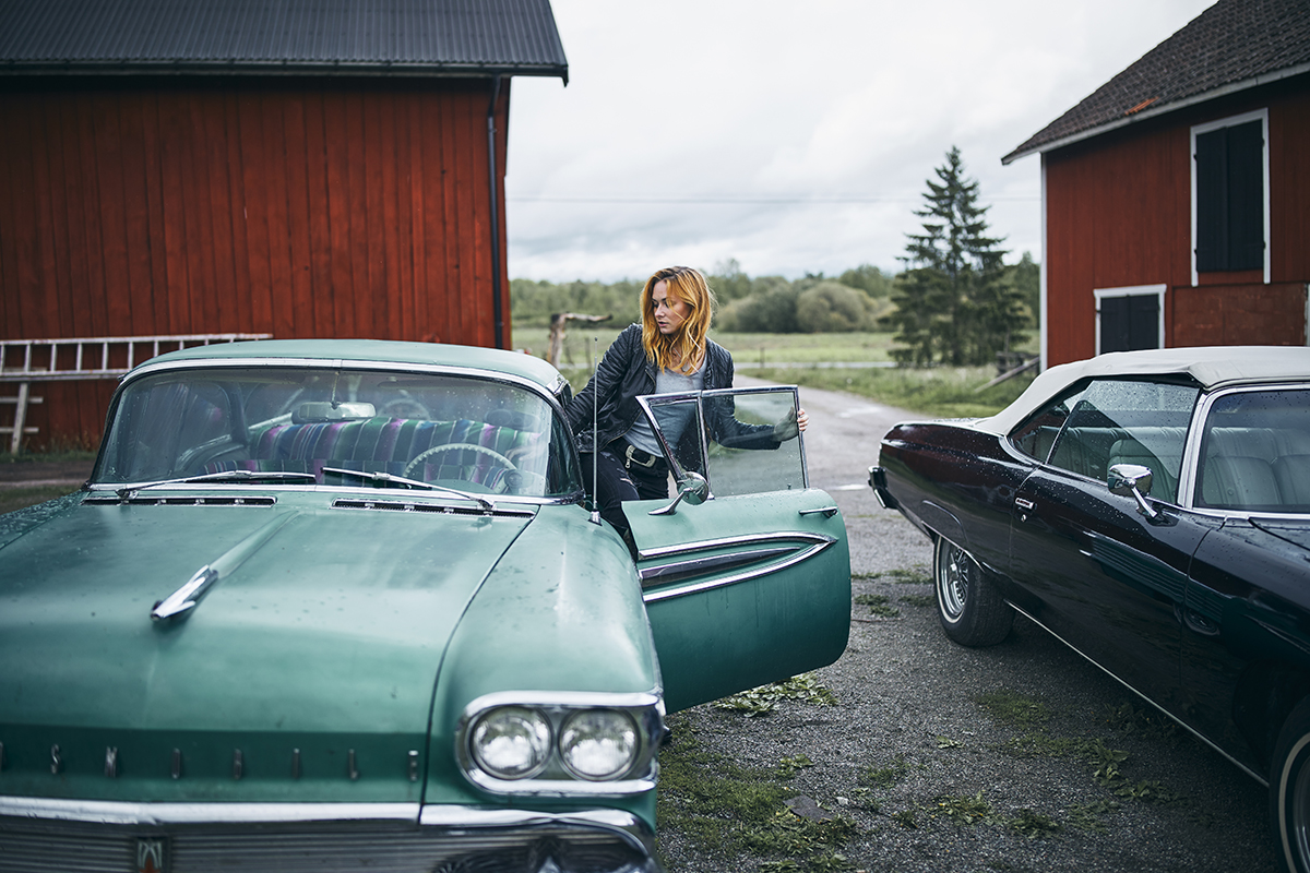 Woman getting into a car by a red house