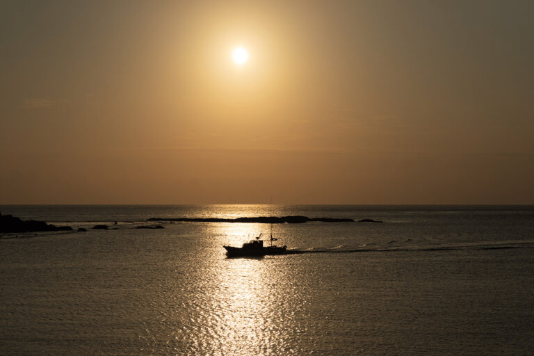 A boat in the water at sunset