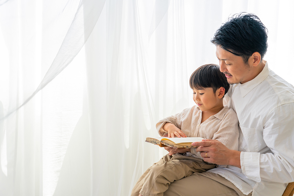 Father and son reading by window