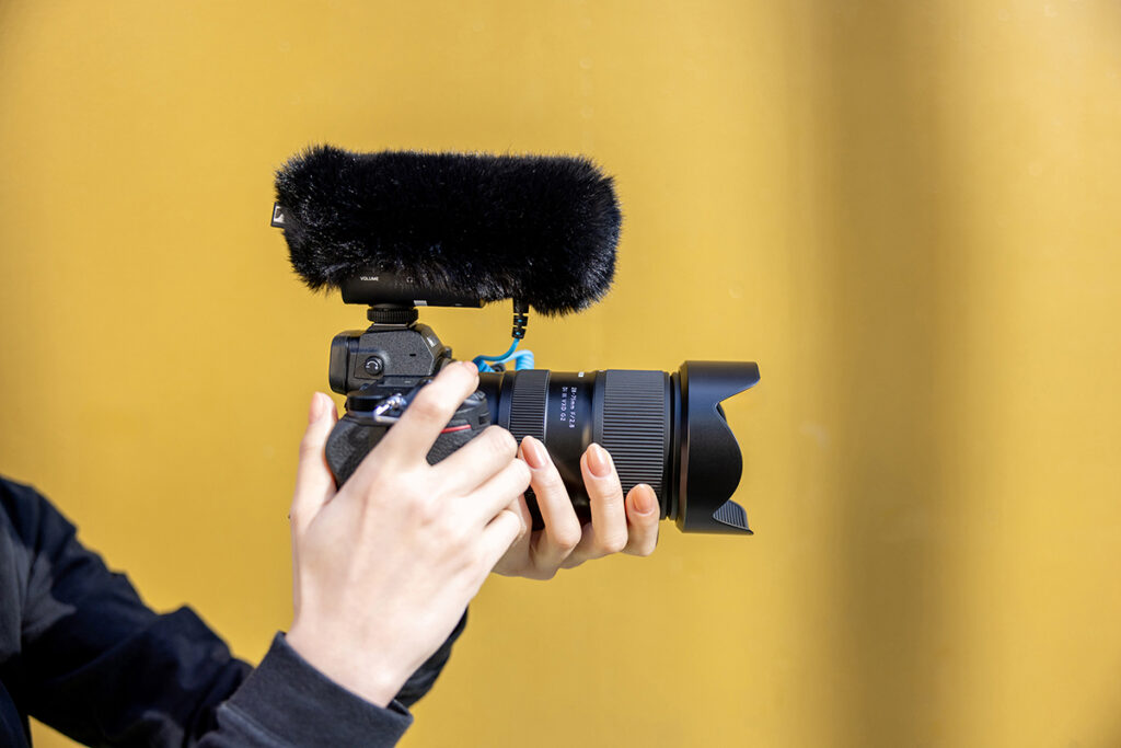 A person adjusts the focus on a professional camera fitted with a large microphone.