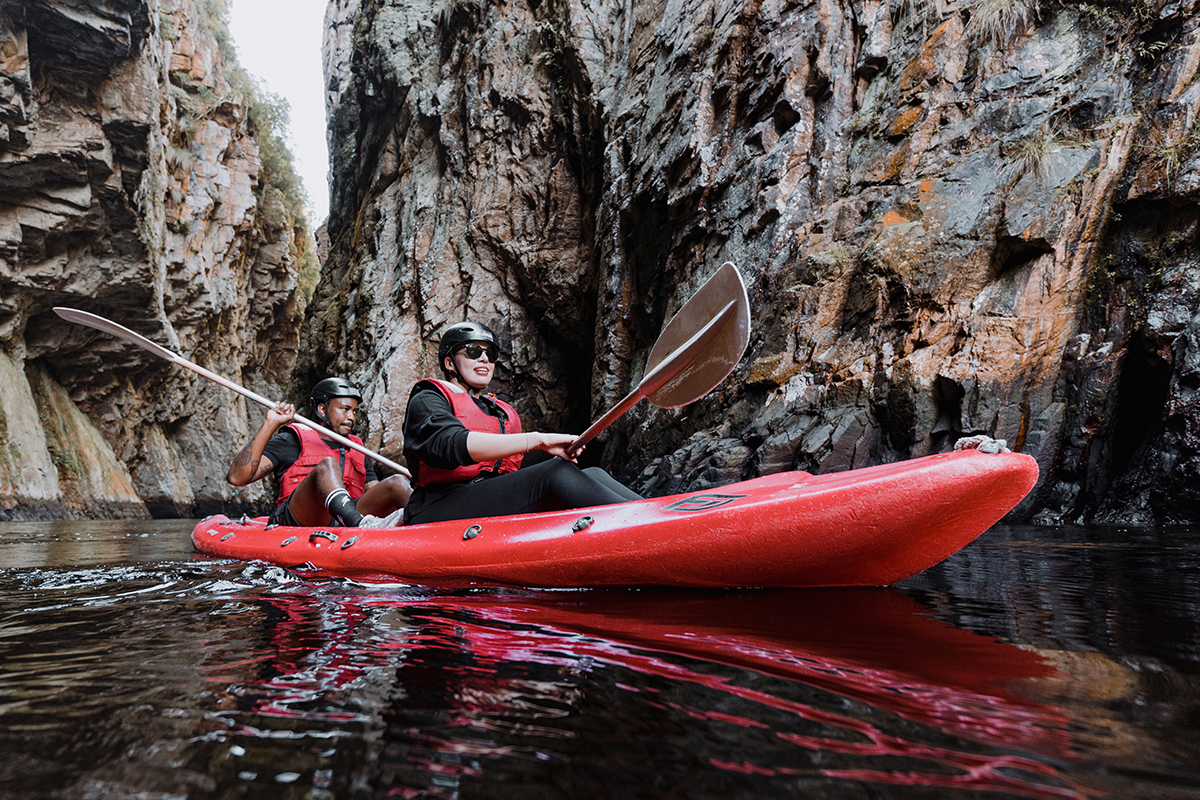 Deux kayakistes sur l'eau entre des falaises rocheuses.