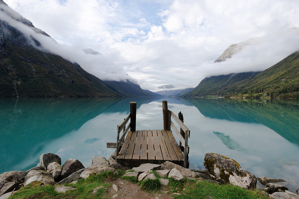 Une vue de l'eau avec des montagnes entourées de nuages.