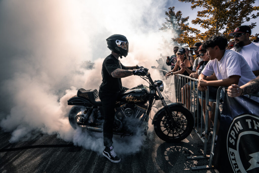 Motociclista hablando a la multitud con humo a su alrededor.