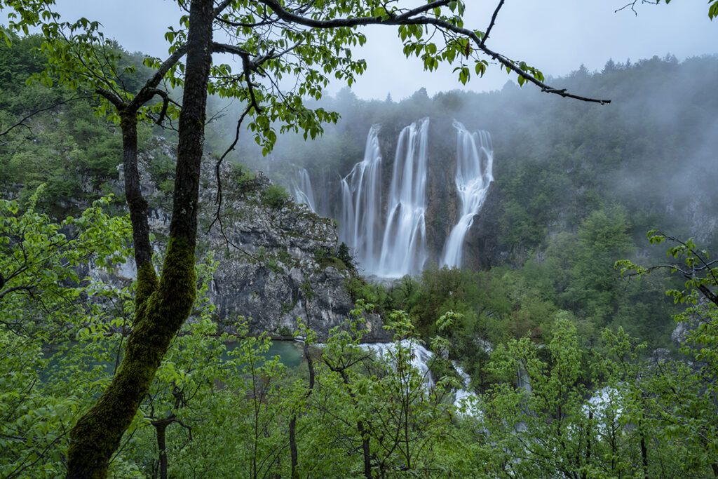 Una vista panorámica de cascadas rodeadas de exuberante vegetación y niebla.