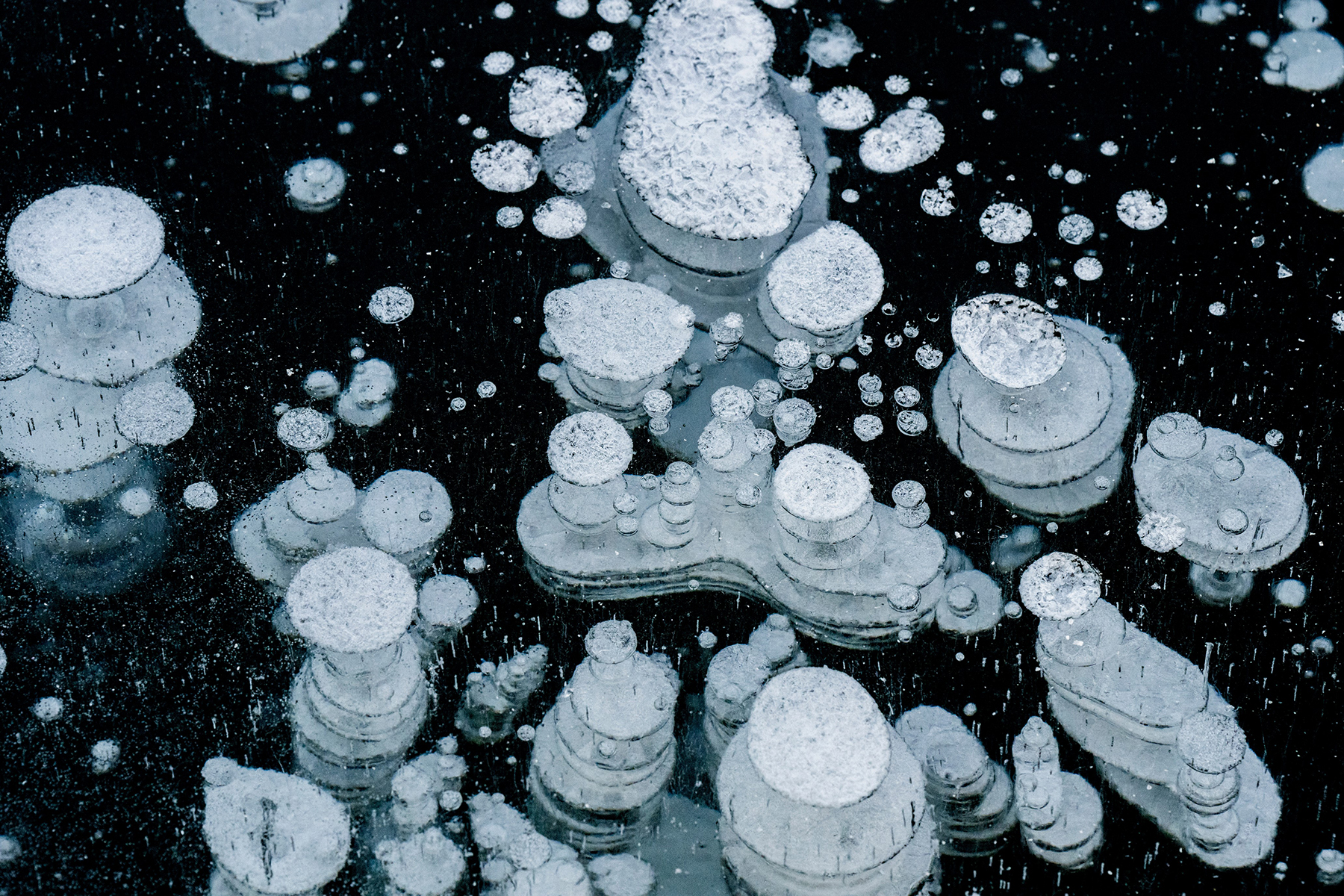Macro shot of frozen bubbles captured in stunning layers beneath the surface of crystal-clear ice.