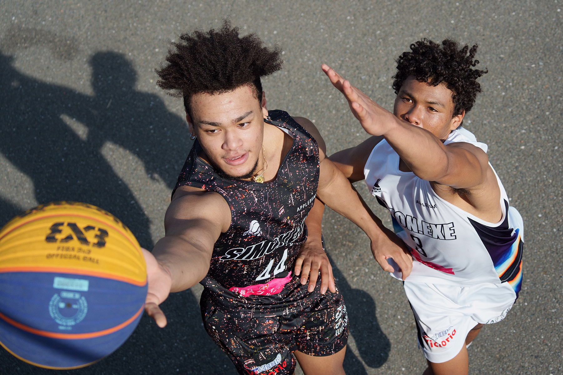 Deux joueurs de basket-ball en action, l'un d'eux tentant d'attraper le ballon au cours d'un match intense.