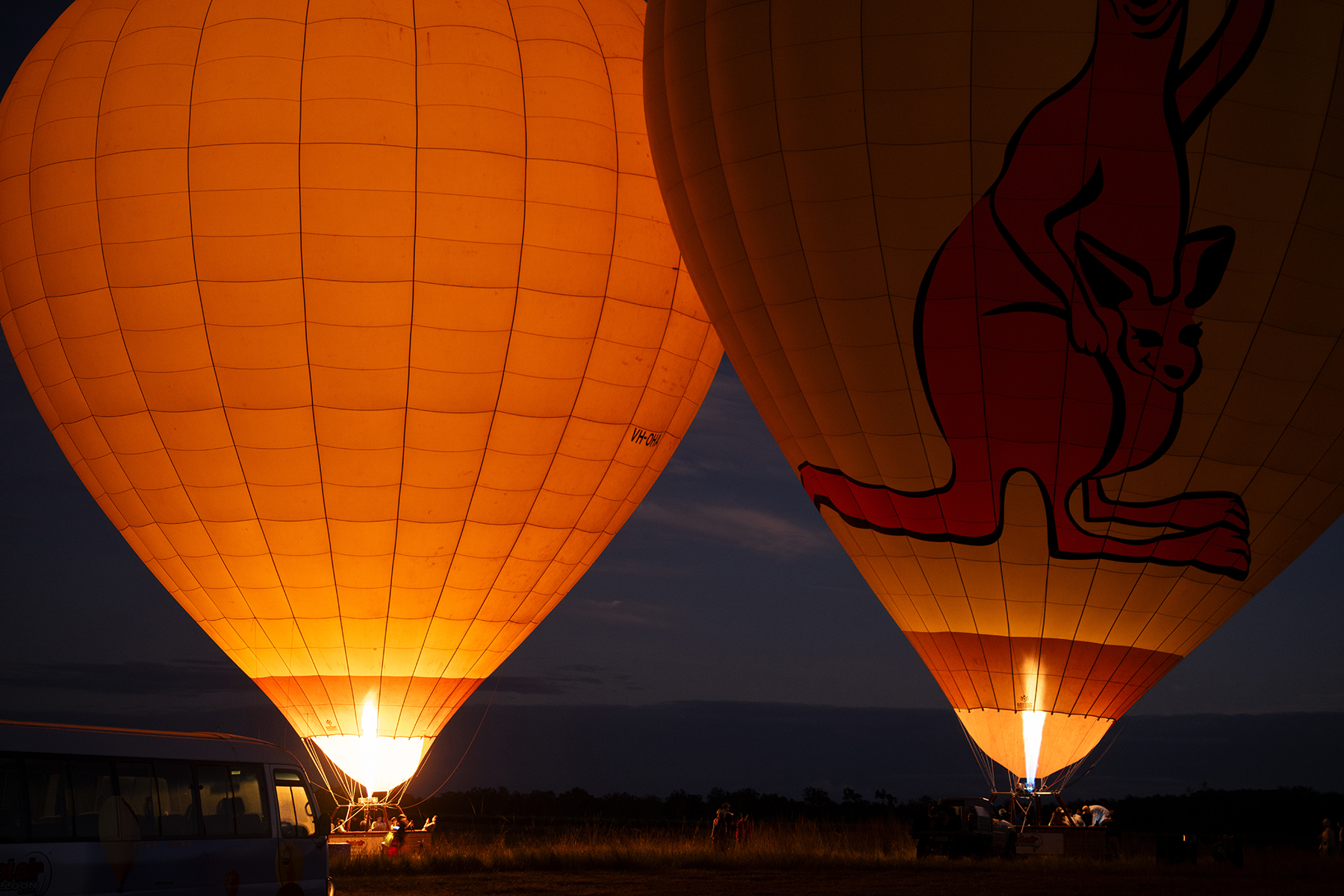 Deux montgolfières illuminées par leurs brûleurs sur fond de ciel nocturne.