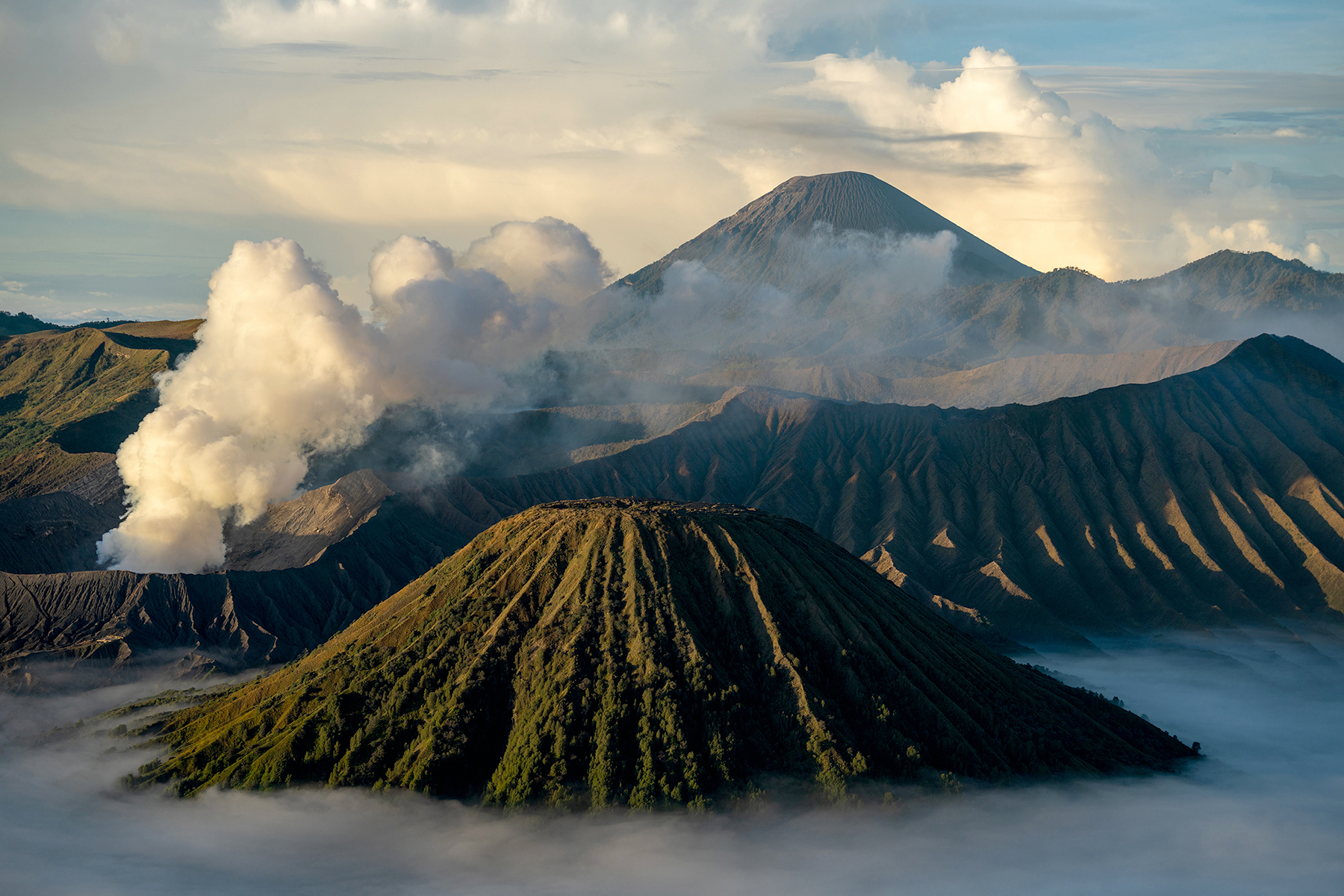 Majestuoso paisaje volcánico en Indonesia con cráteres humeantes y montañas en capas rodeadas de niebla.