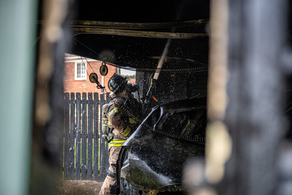 firefighter shooting water into structure