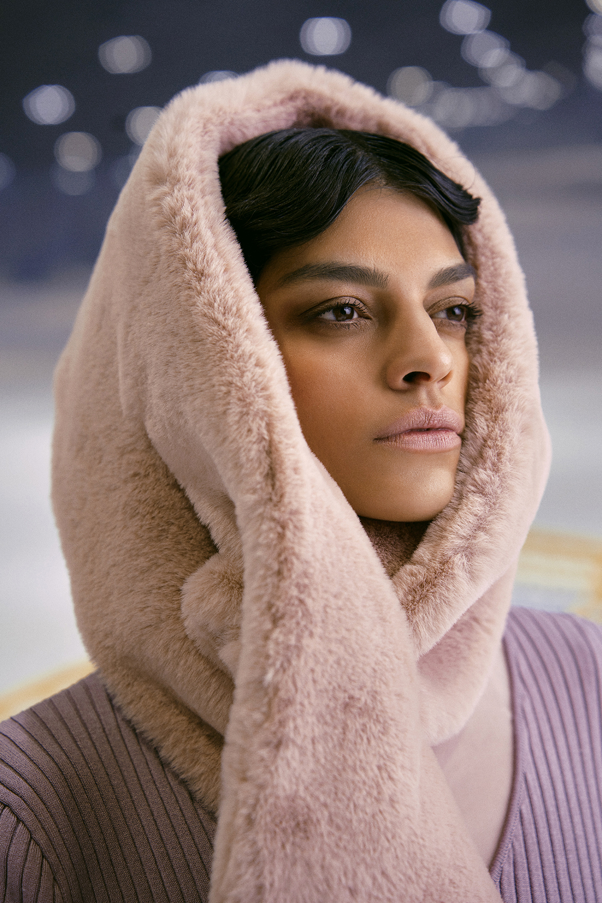 A woman wearing a soft, fur-lined hood with a serene and confident expression.