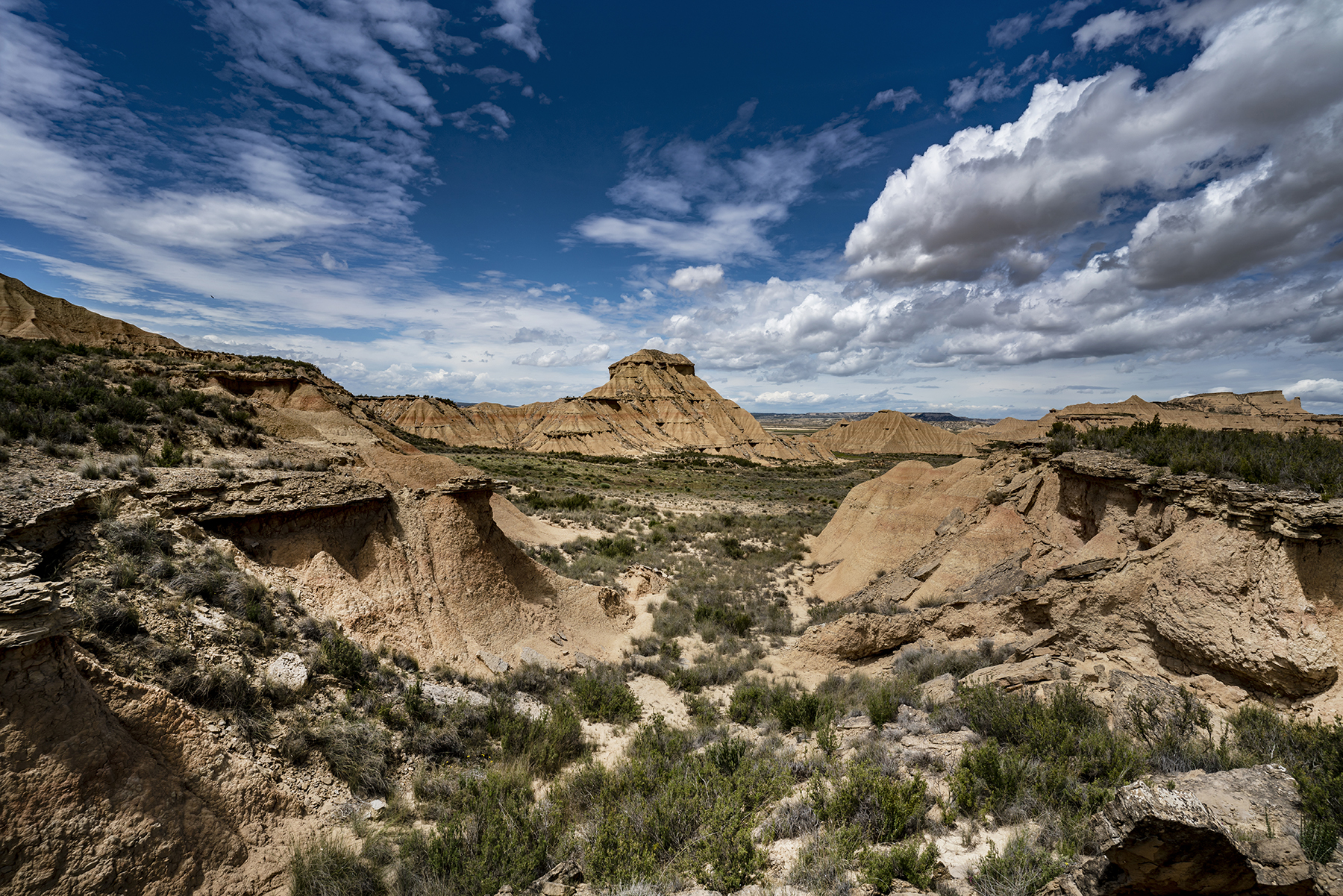 Expansive desert landscape with rugged rock formations and dramatic clouds, showcasing the power of a wide-angle lens for capturing vast and detailed scenery.