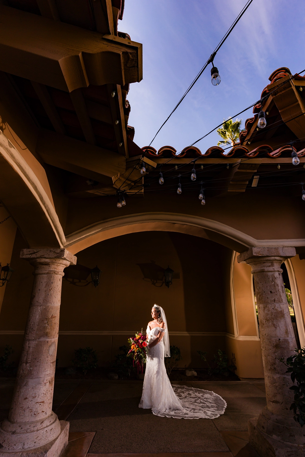 Editorial-style wedding portrait at Tijeras Creek Golf Club featuring a bride in dramatic lighting, framed by Spanish-style architecture for a cinematic effect.