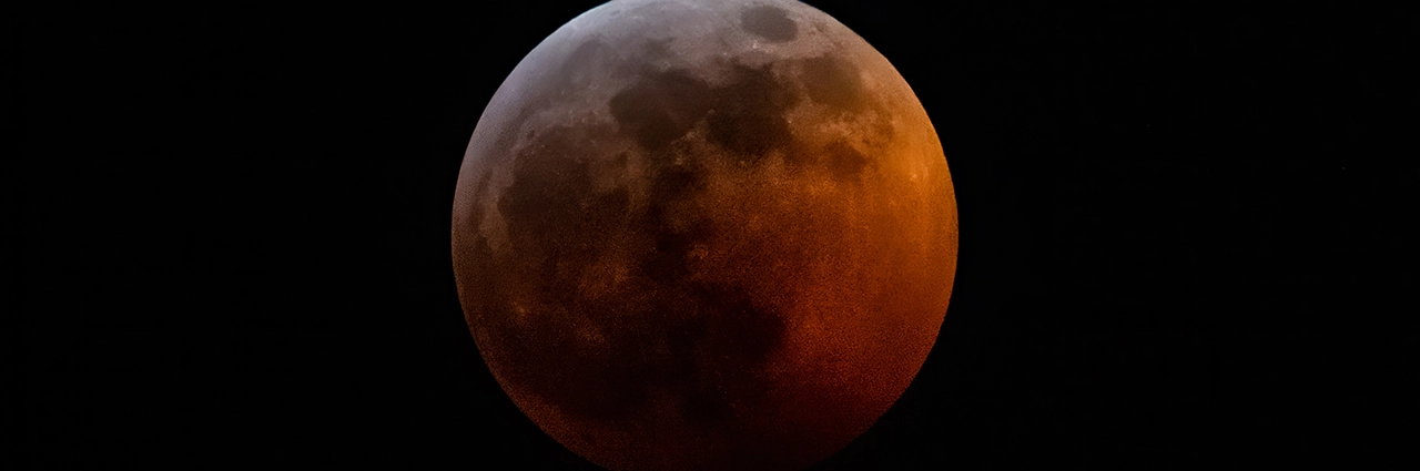 Lunar eclipse photography tips: A detailed image of a blood moon during a total lunar eclipse, showcasing vibrant red and orange hues against the dark sky.