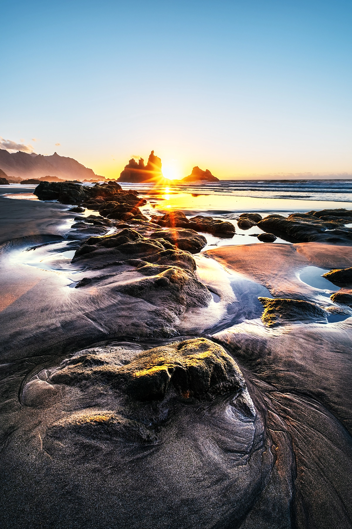 Sunrise over a dramatic coastal landscape with rocks and tide pools, captured using a Tamron Fujifilm wide-angle lens—showcasing dynamic range, sharp detail, and ideal depth for landscape photography enthusiasts.