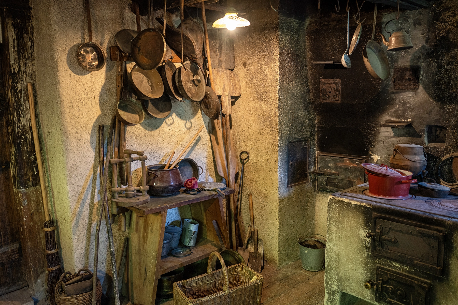 A rustic kitchen inside a traditional Black Forest home (Schwarzwaldhaus), complete with hanging pots, wooden utensils, and a traditional stove—an authentic scene often captured during Rhine River cruise travel photography excursions.