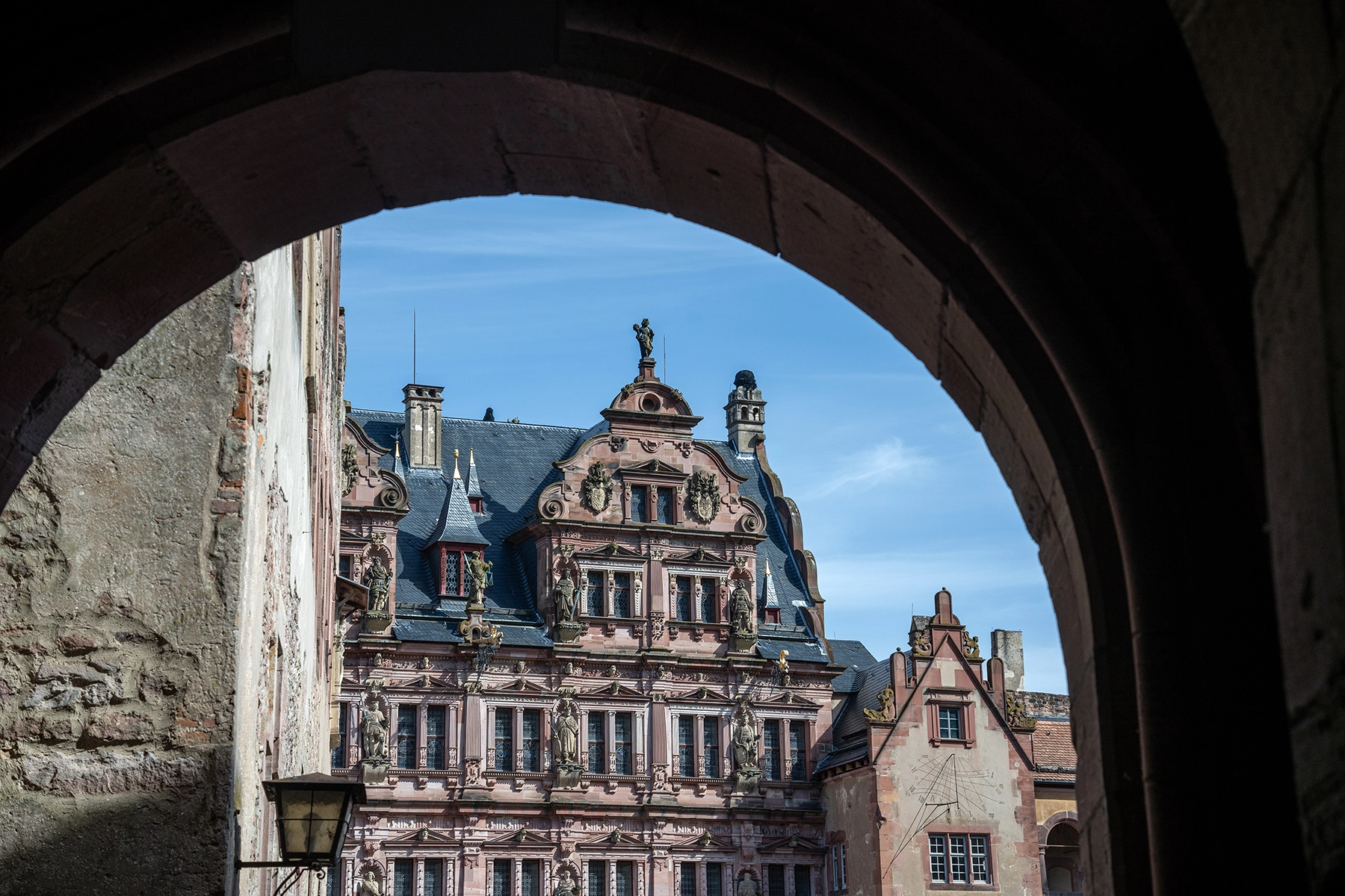 The historic facade of Heidelberg Castle in Heidelberg, Germany framed by a stone archway.