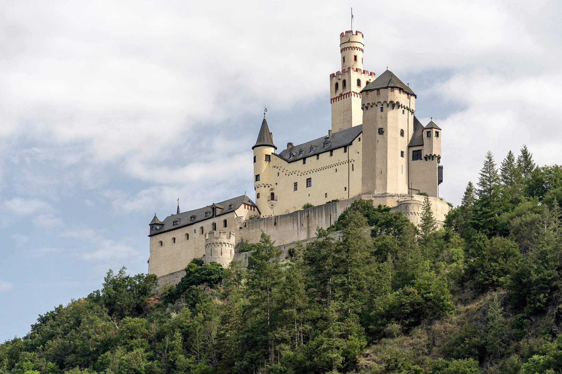 Marksburg Castle perched on a lush hillside overlooking the Rhine River in Germany, a beautiful example of Rhine River cruise travel photography.