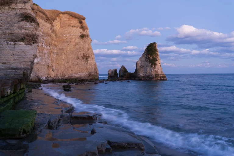 Water lapping at the shore with a rock cliff in the background