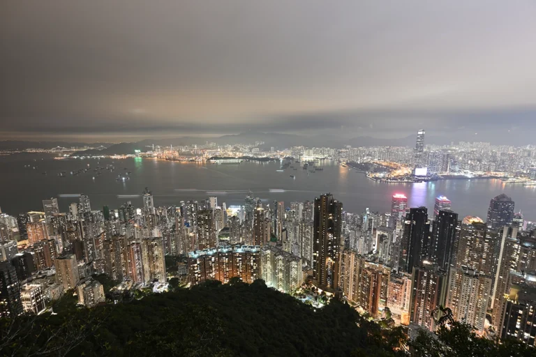 An overhead view of a city skyline at night with lights and water