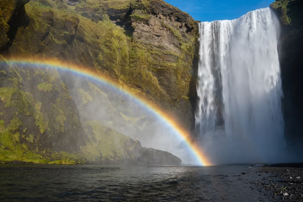 Chute d'eau de Skogafoss en Islande avec un arc-en-ciel au-dessus de l'eau
