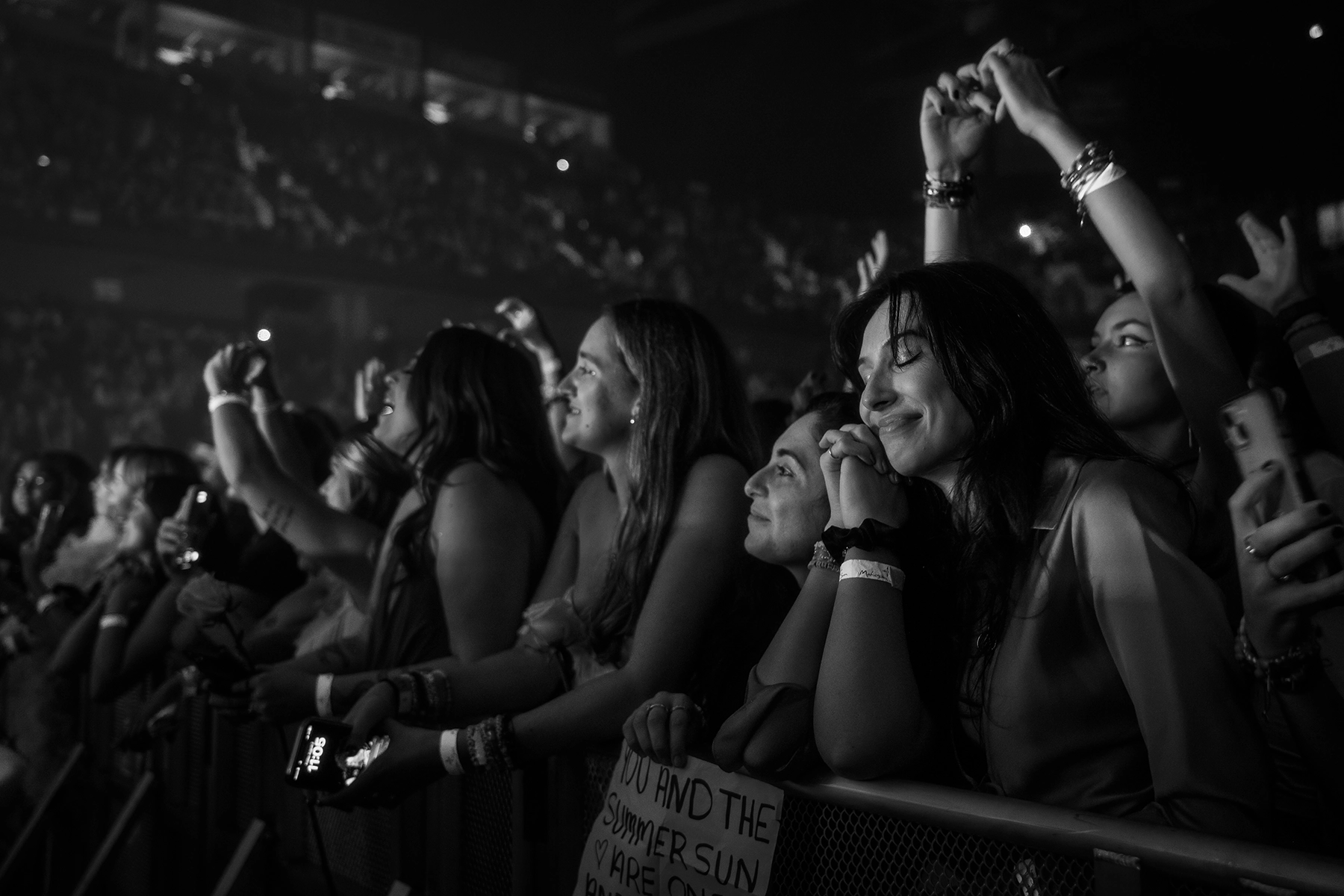Uma foto em preto e branco de fãs contra uma barricada curtindo a música