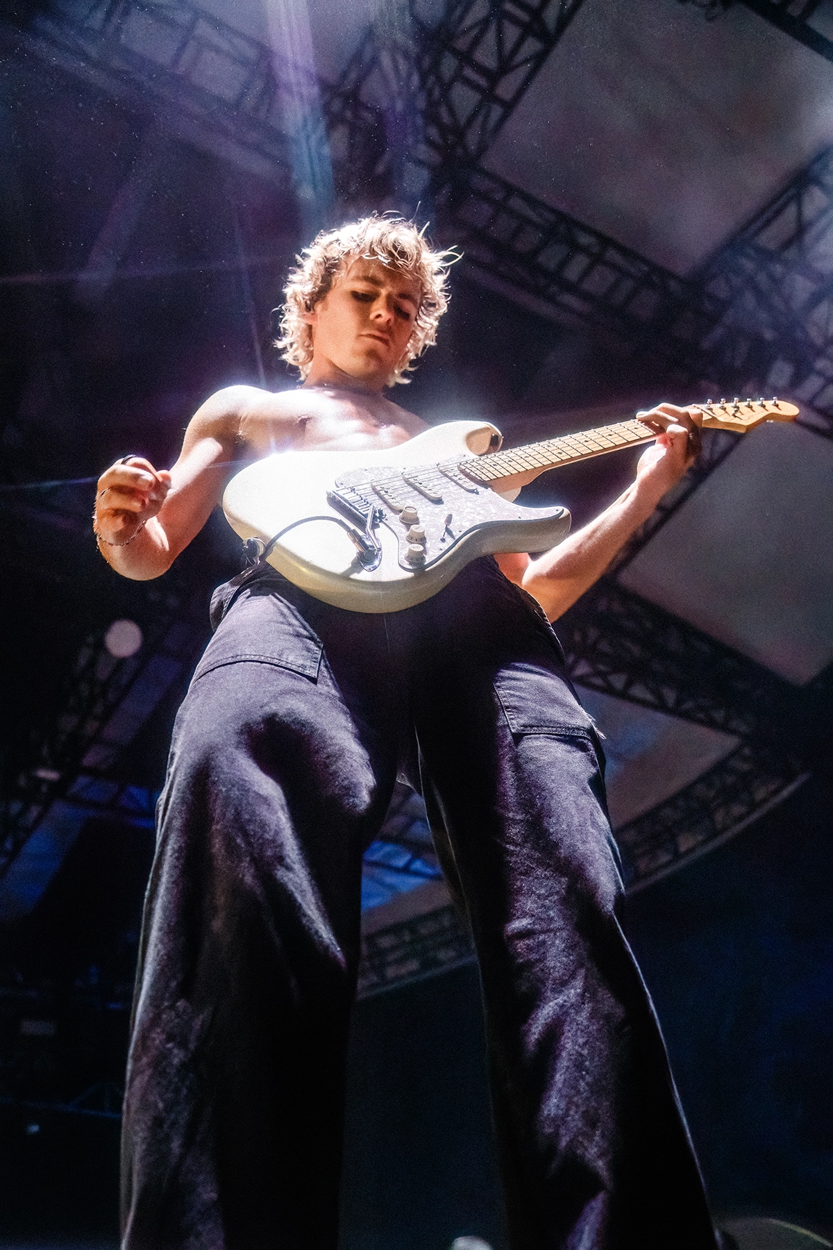 Um close-up de um guitarrista sem camisa da banda The Driver Era