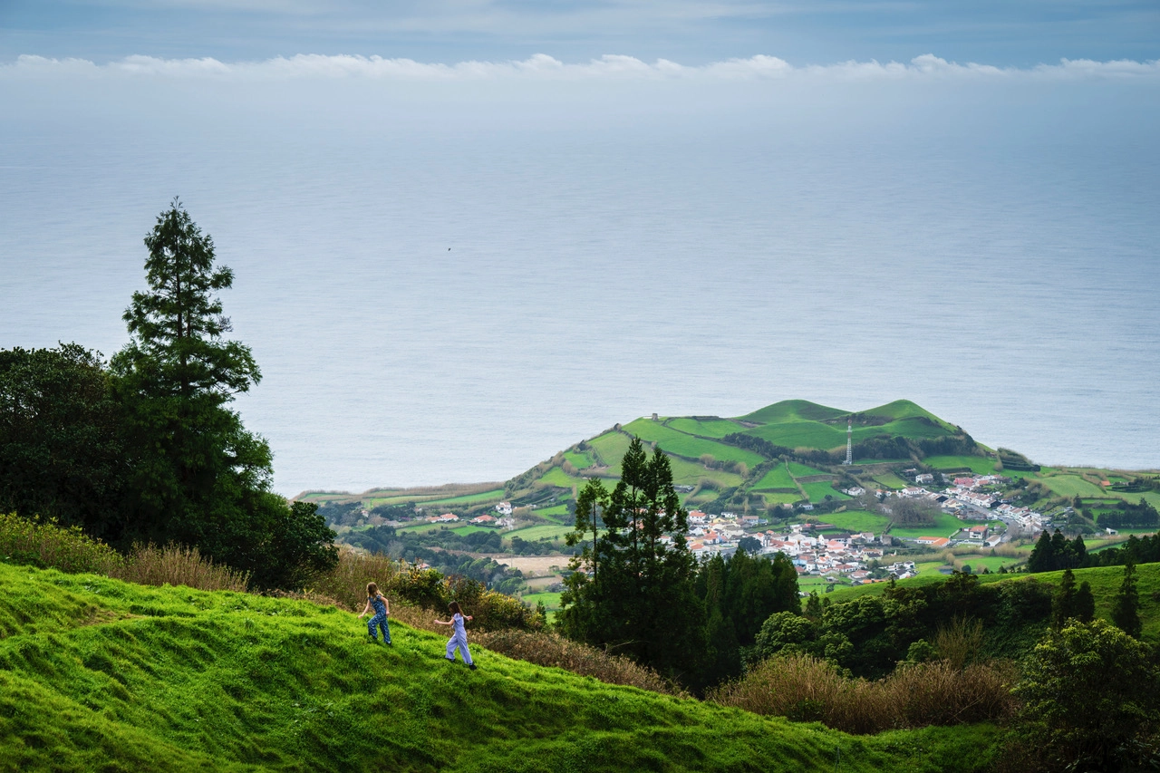 Children running on hillside above ocean – how to photograph the Azores with scale, storytelling, and sweeping São Miguel views.