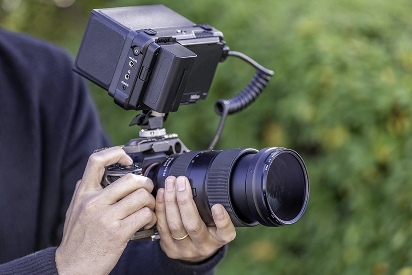 Un videógrafo muestra los aspectos básicos de la grabación de vídeo con una cámara sin espejo equipada con un objetivo Tamron y un monitor externo.