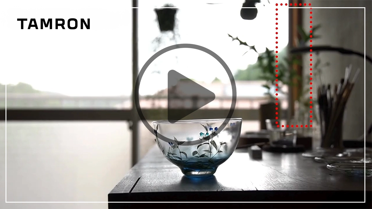 Un cuenco de cristal transparente con motivos florales pintados está enfocado sobre una mesa, ilustrando la respiración mínima del enfoque en entornos de videografía controlada.