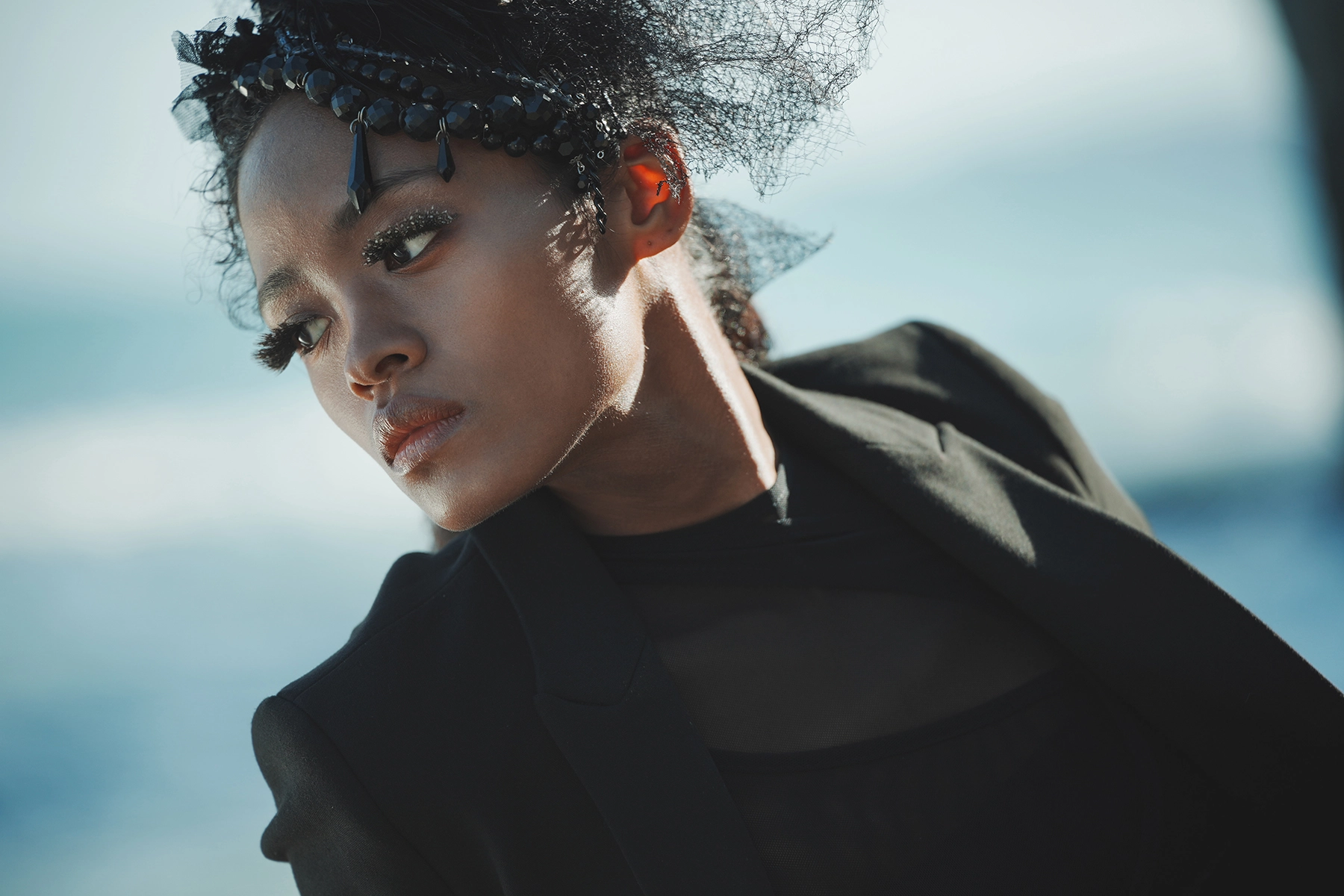 Portrait extérieur en gros plan d'une femme sous un éclairage et un style de mode spectaculaires, mettant en évidence la précision de la mise au point des yeux et du bokeh, capturé à l'aide du moteur autofocus linéaire VXD de Tamron pour des résultats d'une extrême netteté.