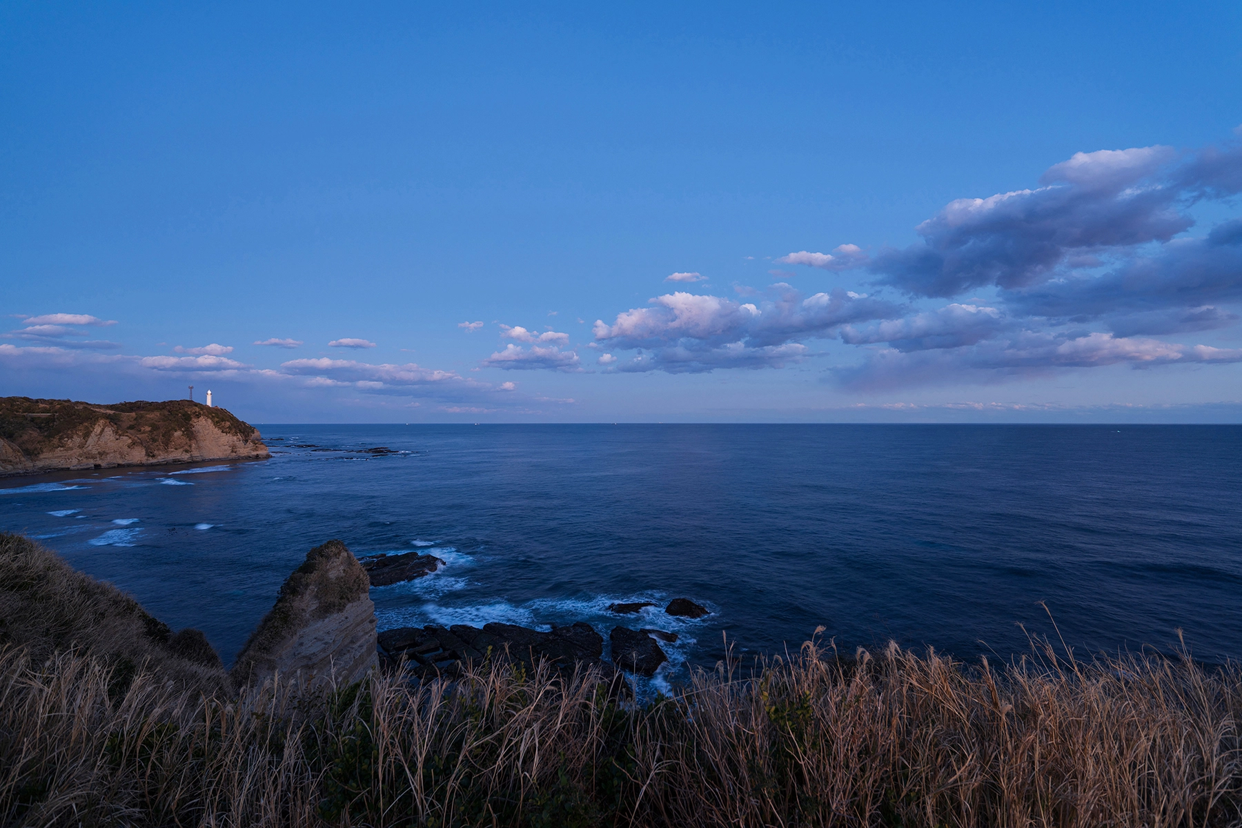 Paysage côtier crépusculaire avec un phare et un horizon océanique, capturé à 16 mm lors de l'examen du Tamron 16-30 mm F2.8 G2, mettant en évidence la netteté d'un bord à l'autre.