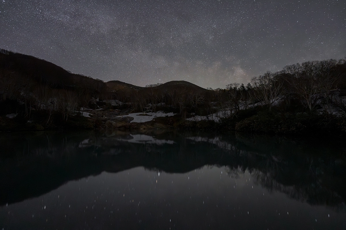 Paisaje nocturno con cielo estrellado y reflejo de montaña capturado utilizando Astro Focus Lock para astrofotografía con TAMRON Lens Utility™.