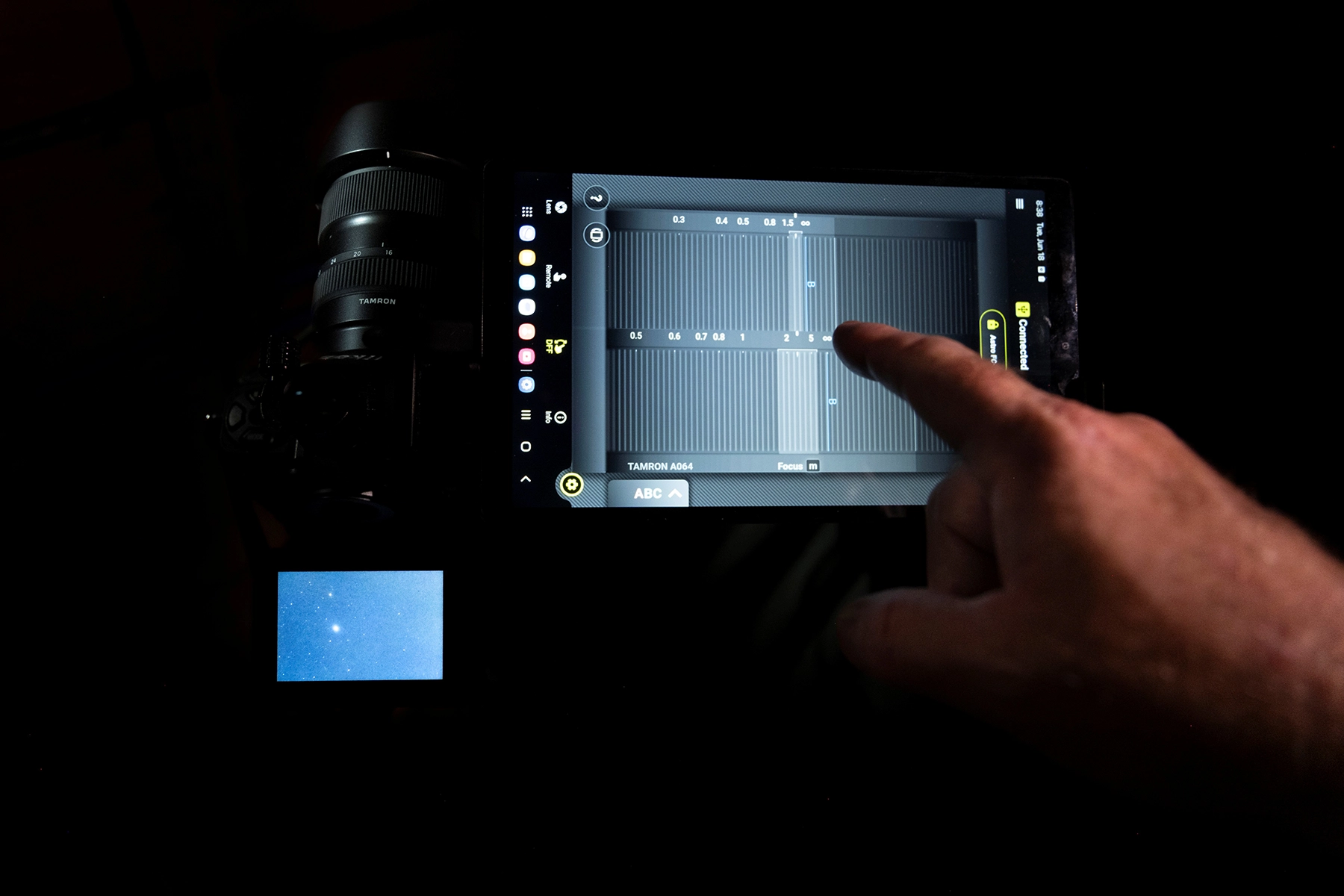 Fotógrafo utilizando Astro Focus Lock en TAMRON Lens Utility™ a través del smartphone para ajustar el enfoque de las estrellas durante la fotografía del cielo nocturno con la cámara y el objetivo conectados.