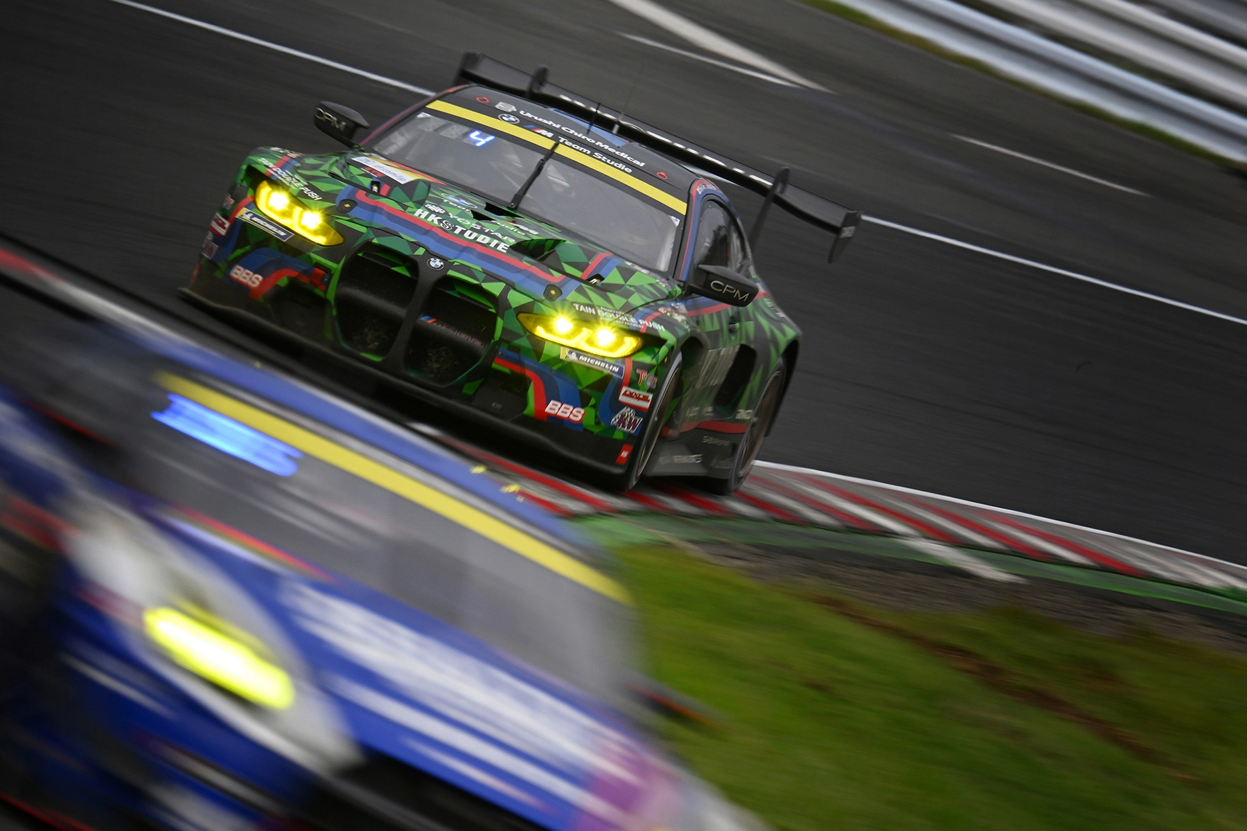 Captura a velocidad de obturación lenta de un coche de carreras tomando una curva a gran velocidad, con un desenfoque intencionado del fondo y del primer plano que acentúa la velocidad y la intensidad, captada mediante técnicas de fotografía deportiva dinámica.