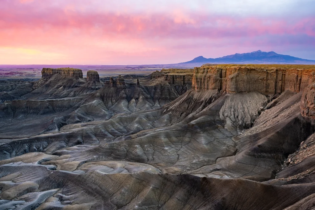 Un amanecer con las montañas de La Sal al fondo y el paisaje desértico en primer plano.
