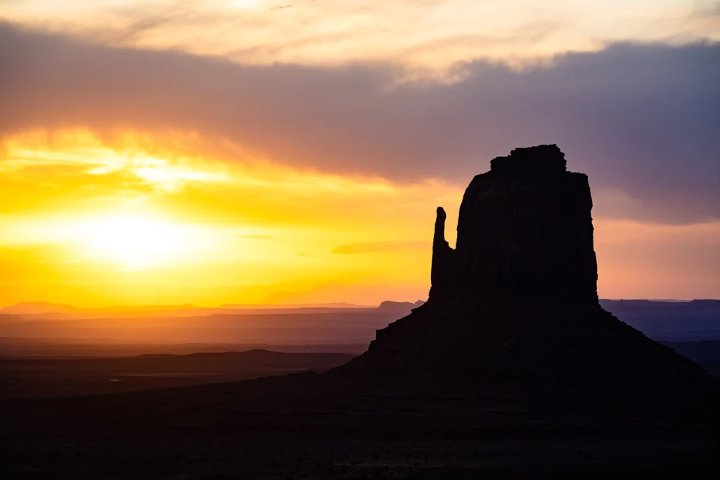 Fotografía de una formación rocosa con silueta en Monument Valley durante el amanecer