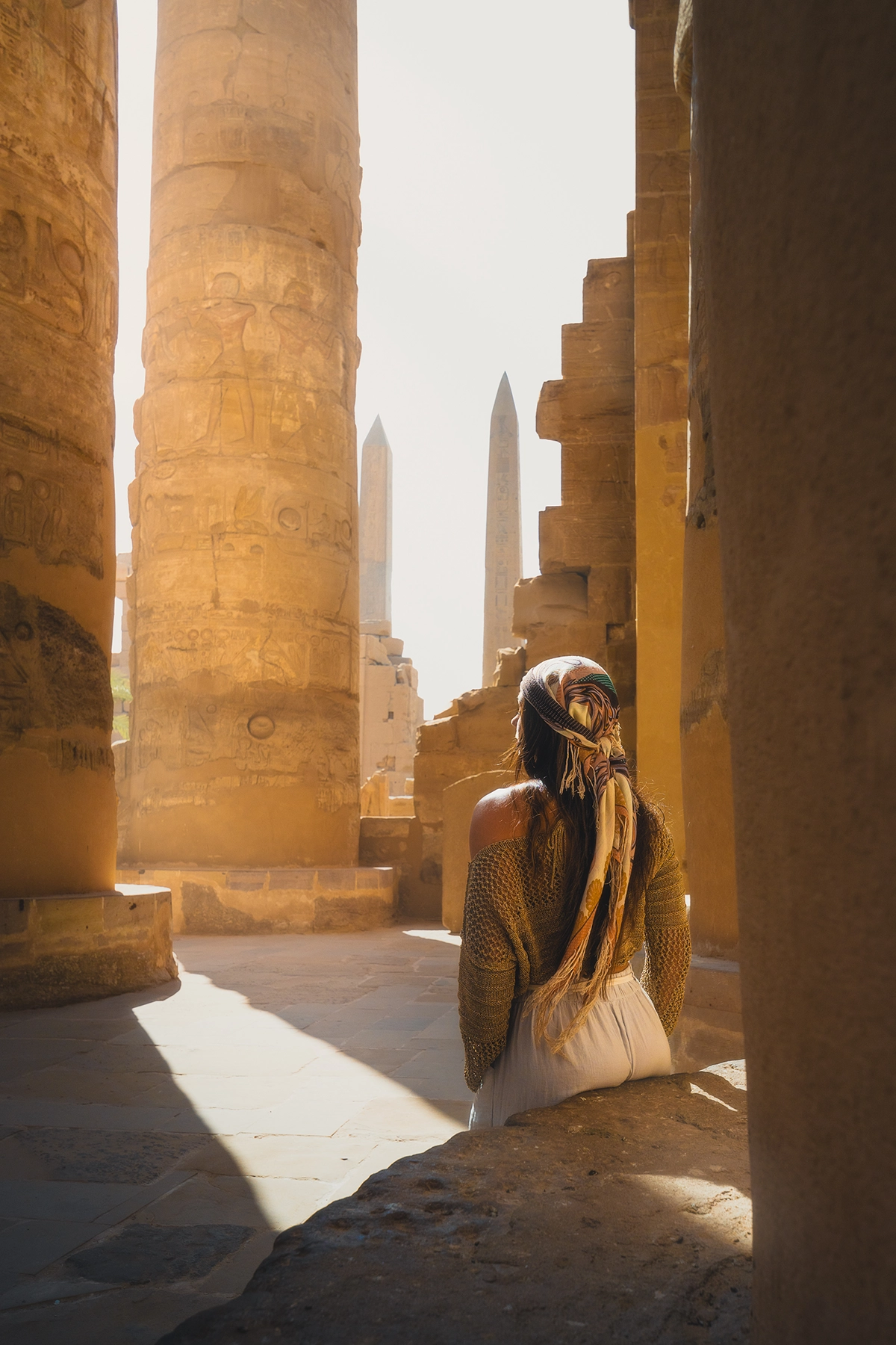 Templo de Karnak en Luxor con una pasarela de pilares con una mujer mirando a través de los pilares