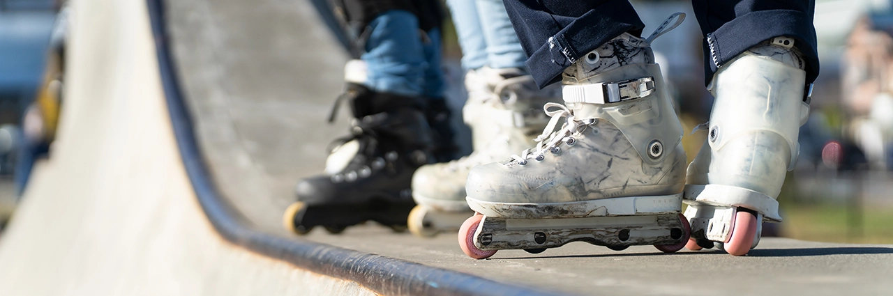 Primer plano de unos pies con patines blancos y negros en un parque de patinaje.