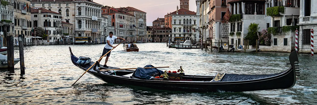Un gondolier longe le Grand Canal au coucher du soleil, mettant en valeur l'atmosphère de la ville flottante de l'Italie pour ce guide de photographie de voyage de Venise.