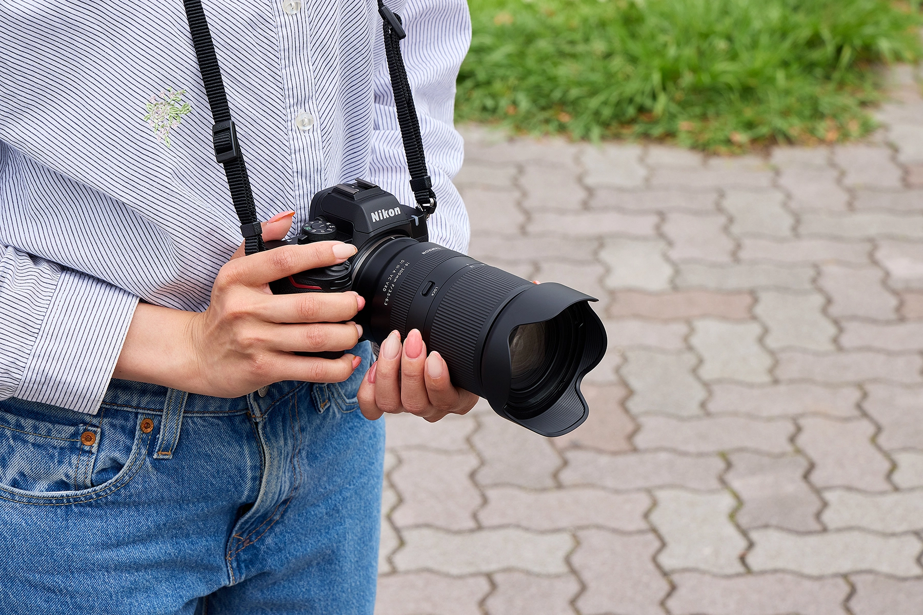 Pessoa segurando uma câmera com uma lente Tamron 18-300 mm com zoom para montagem Nikon Z.