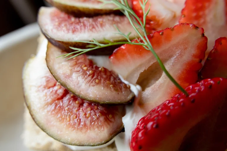 Strawberries a sprig of dill and seeded fruit in a bowl.