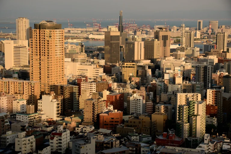 A city scene with high rise buildings with water in the background.